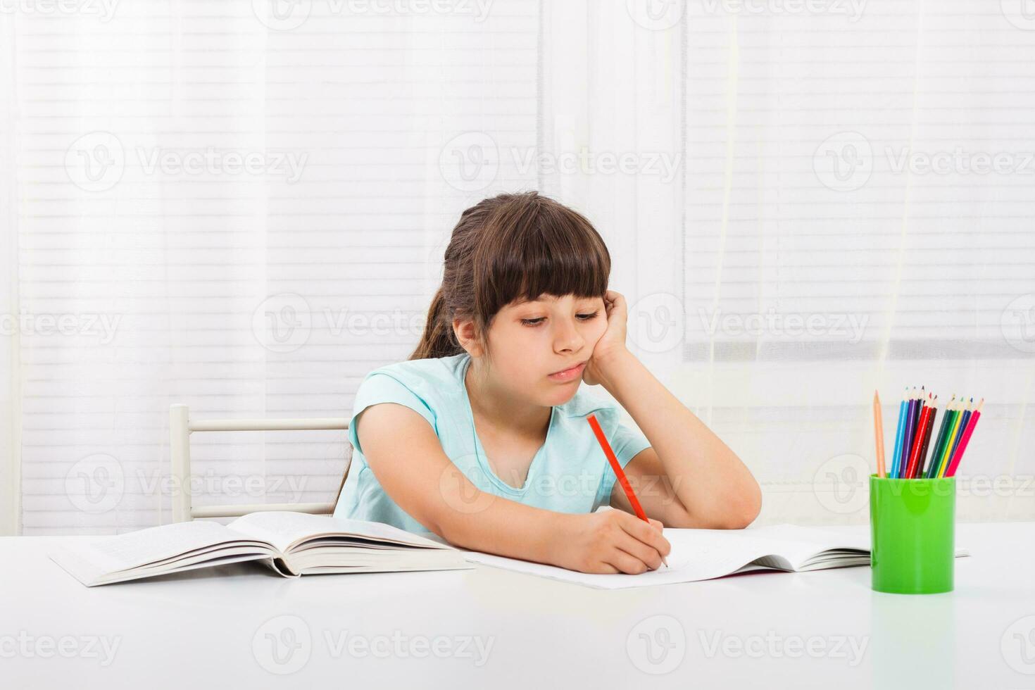 Little girl must stay at home and do her homework,but she would rather play outside. photo