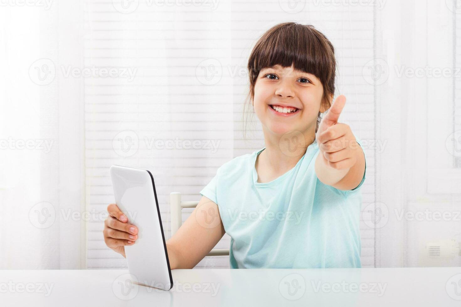 Little girl using digital tablet and showing thumb up photo