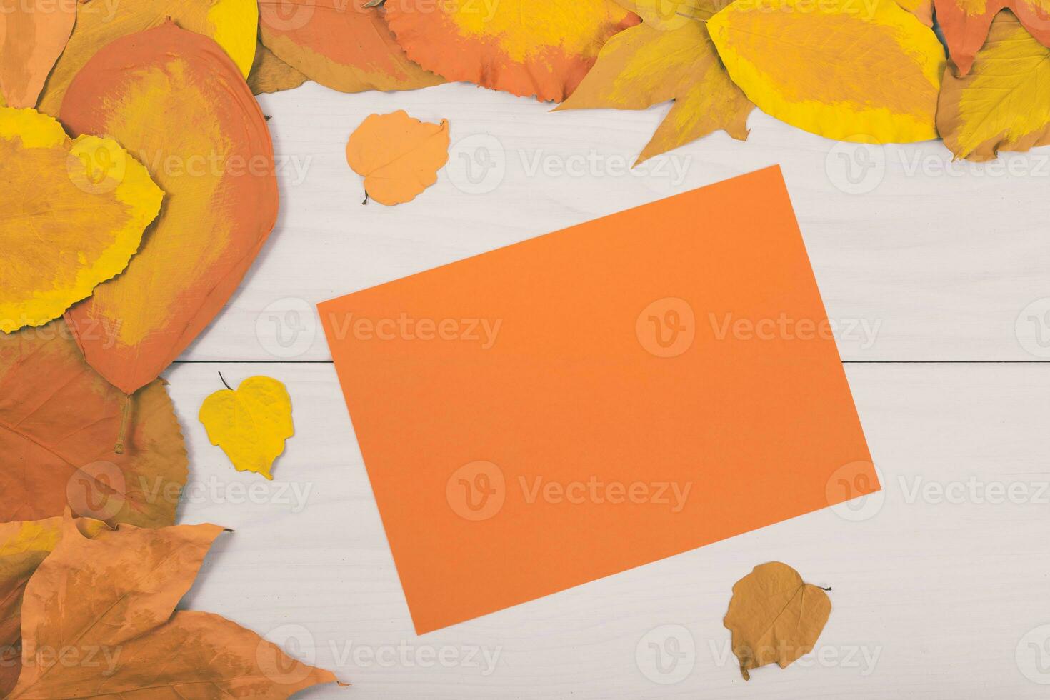 Autumn leaves and yellow paper on wooden table photo