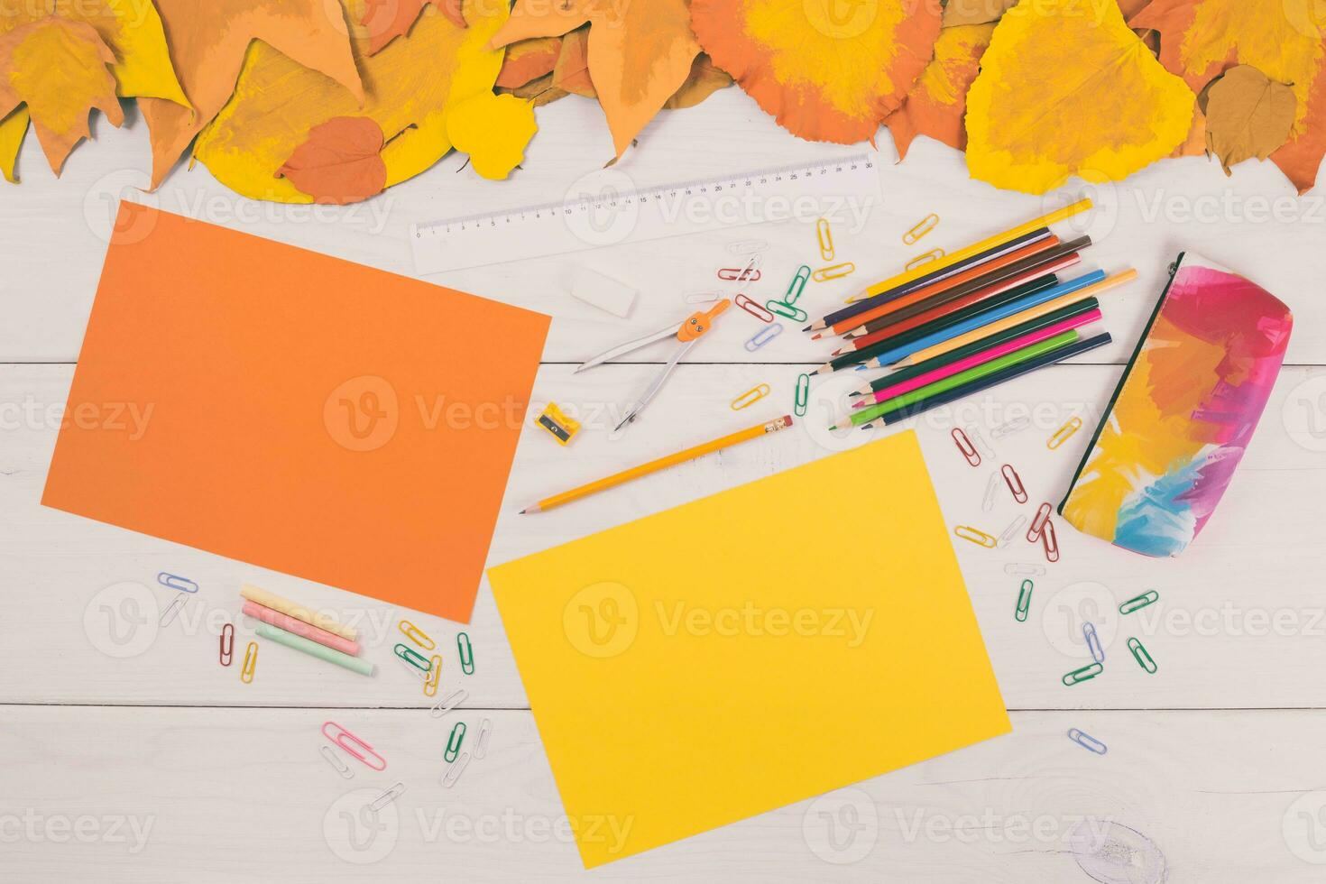 Autumn leaves and school supplies on white wooden table top view photo