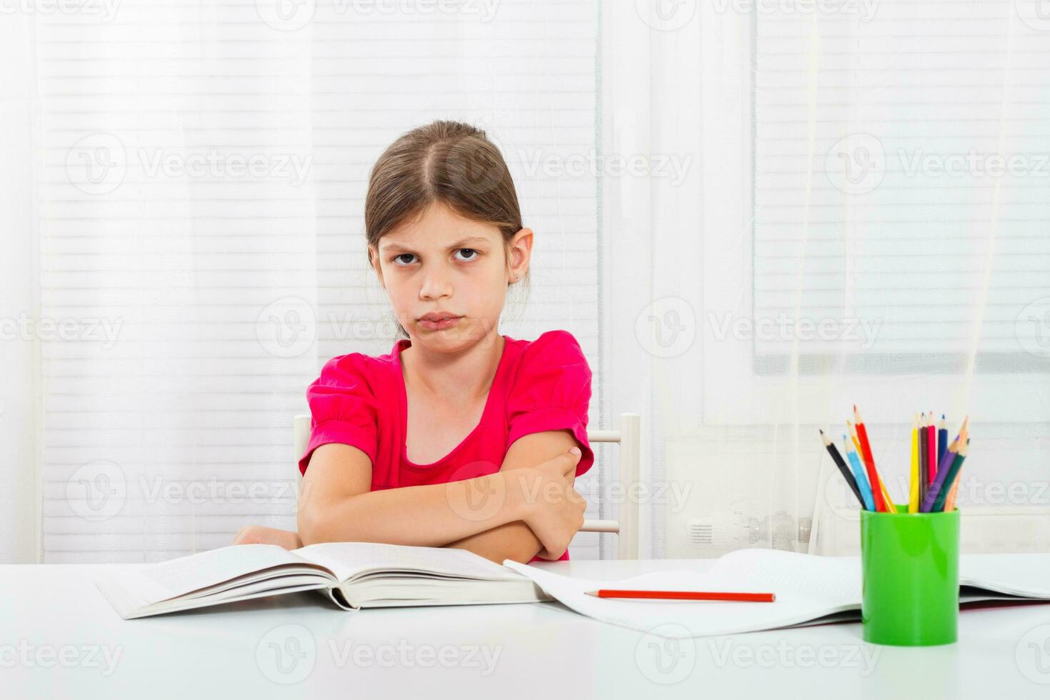 Little girl must stay at home and do her homework,but she would rather play outside. photo