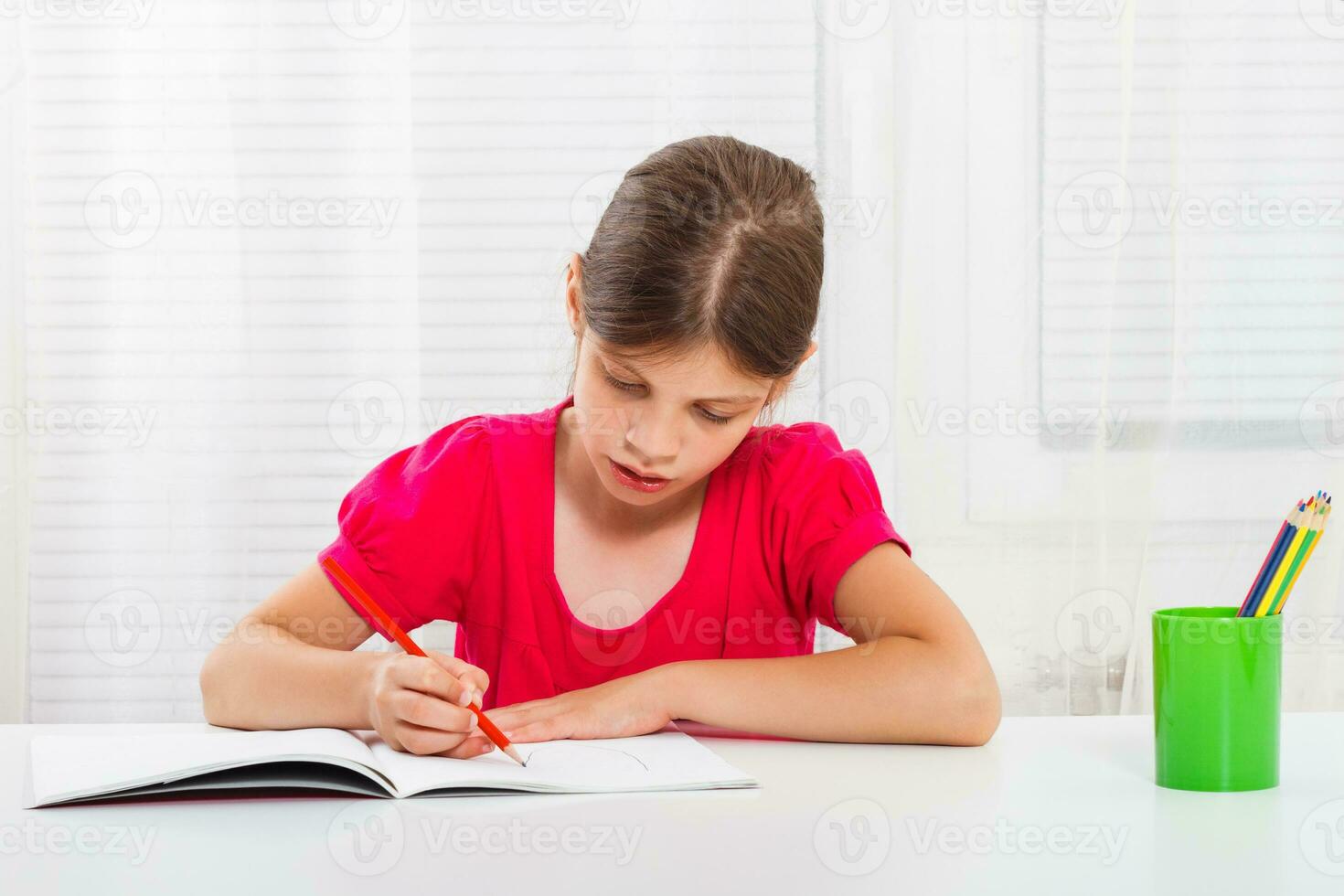 linda pequeño niña es haciendo su deberes foto