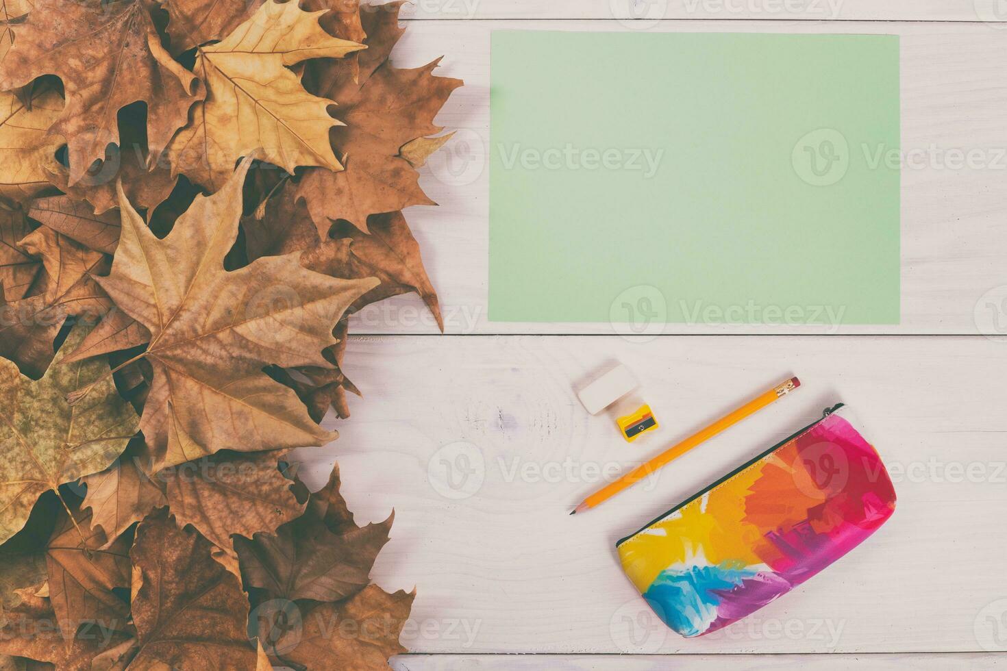 Autumn leaves and school supplies on wooden background photo