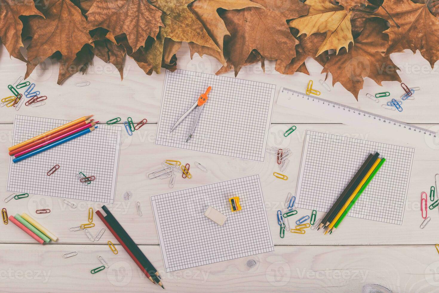 Autumn school supplies on a white wooden table with autumn leaves photo