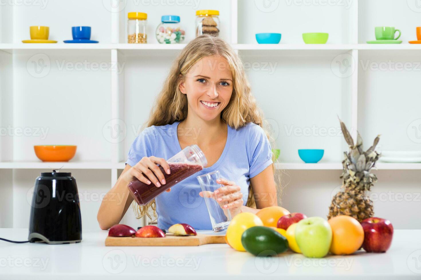 Beautiful girl enjoys making smoothie at her home photo