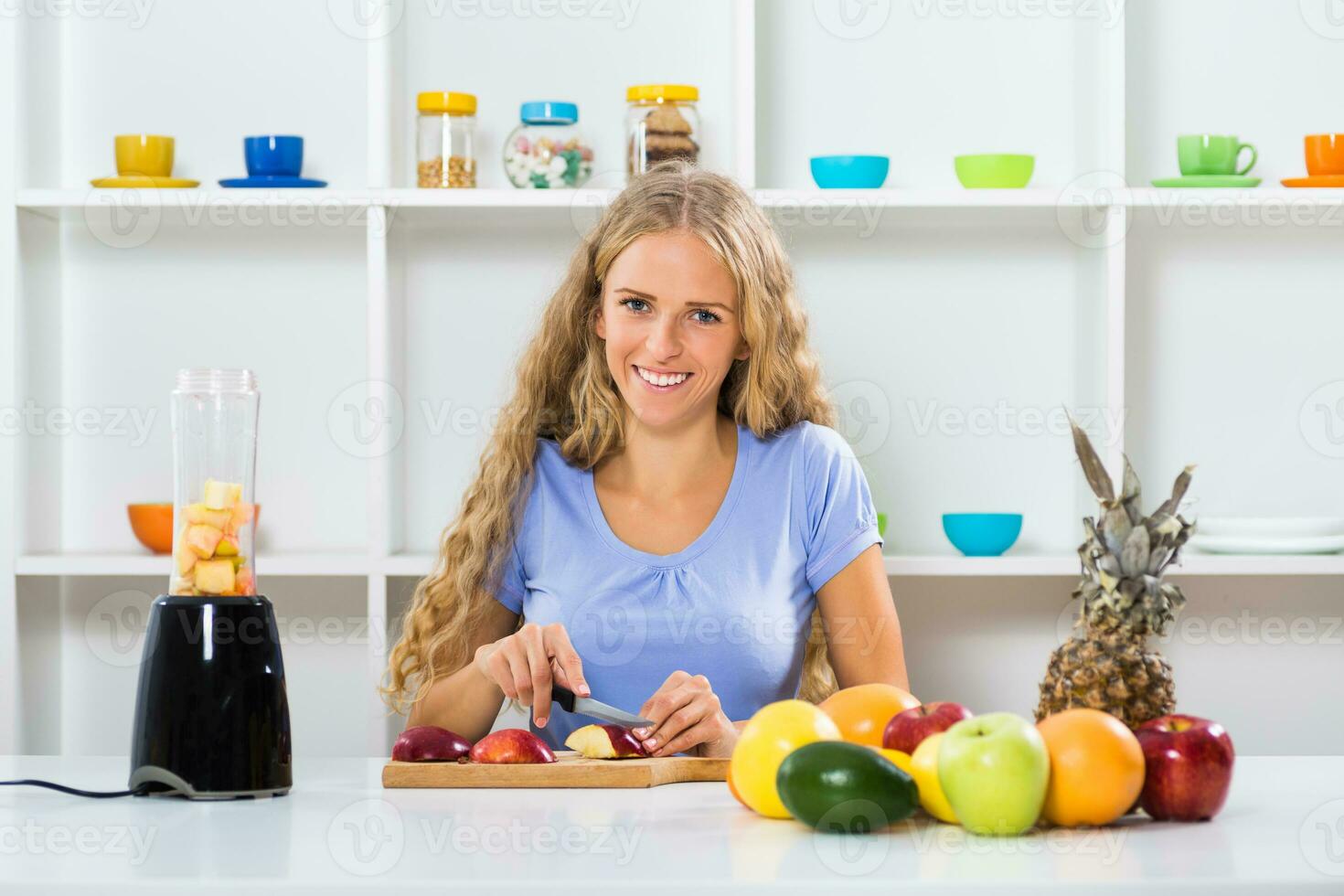 Beautiful girl enjoys making smoothie at her home photo