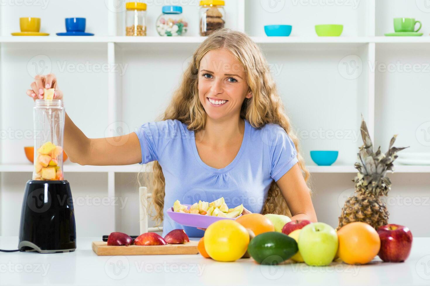 Beautiful girl enjoys making smoothie at her home photo