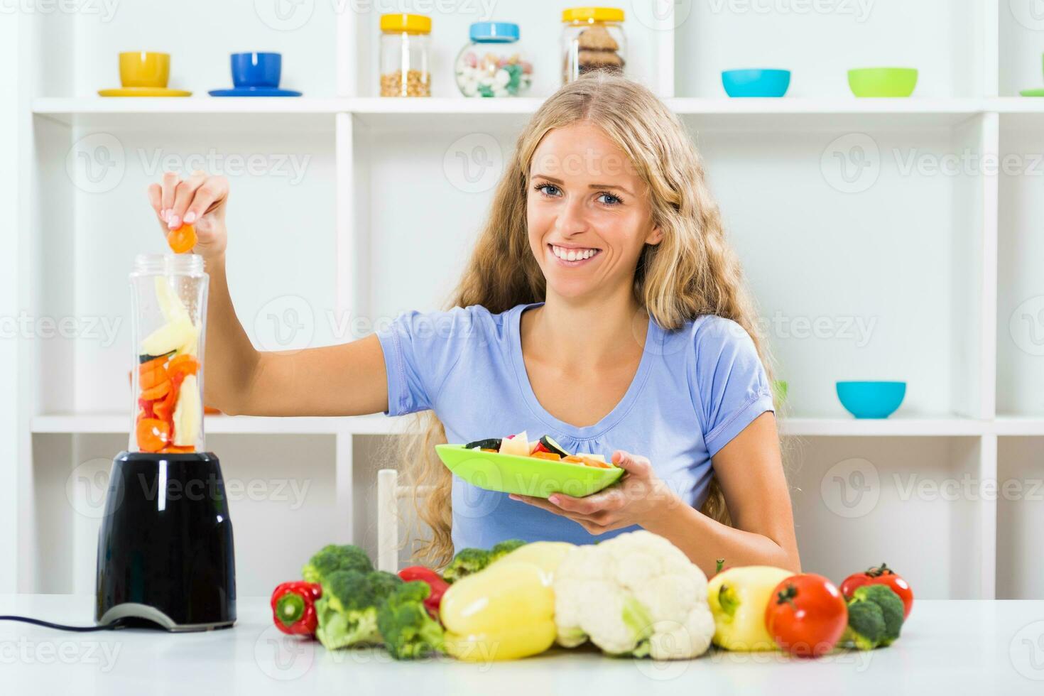 Beautiful girl enjoys making smoothie at her home photo