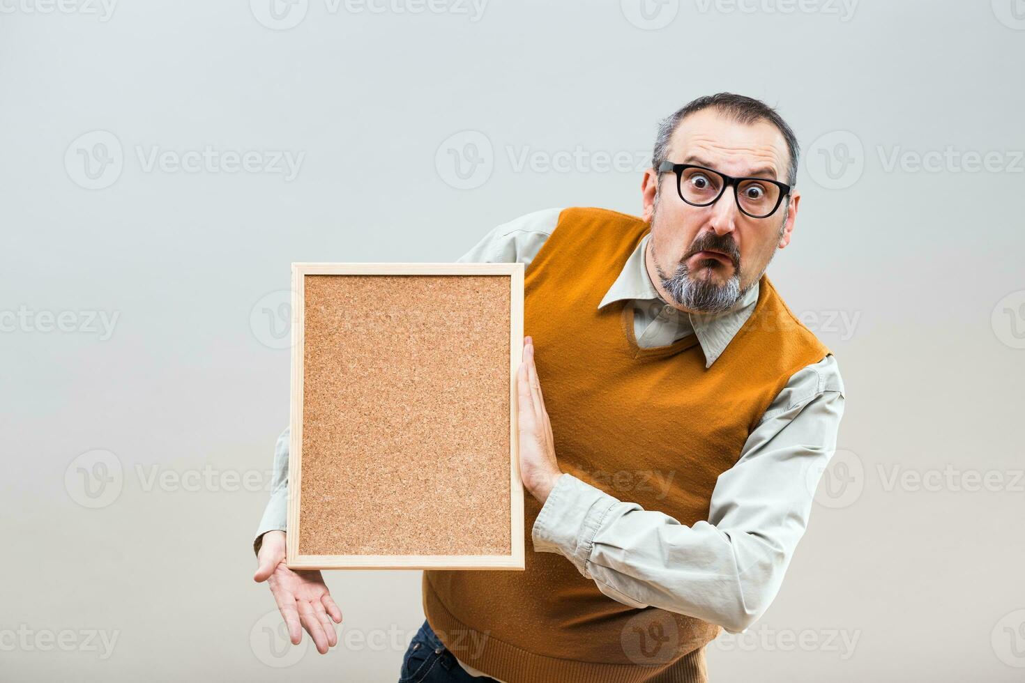 Nerdy businessman is confused because of something while holding empty cork board photo