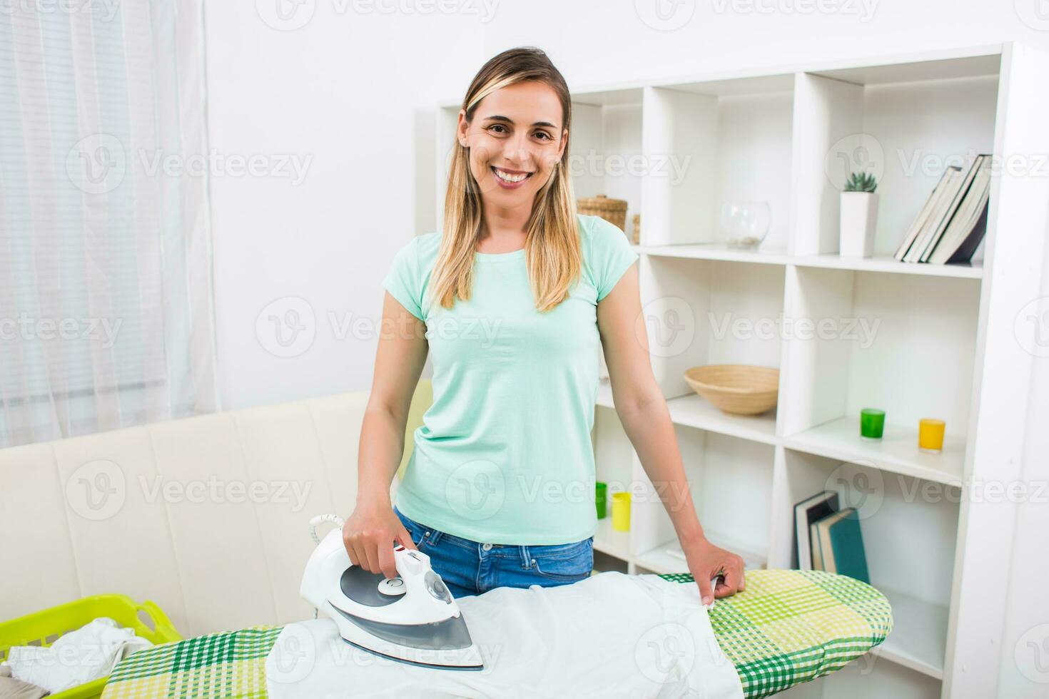 Beautiful woman ironing clothes at her home photo
