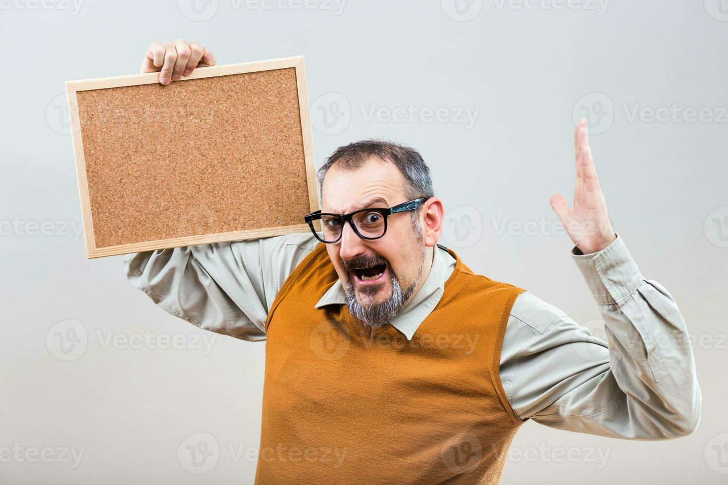 Nerdy businessman is in panic because of something while holding empty cork board photo