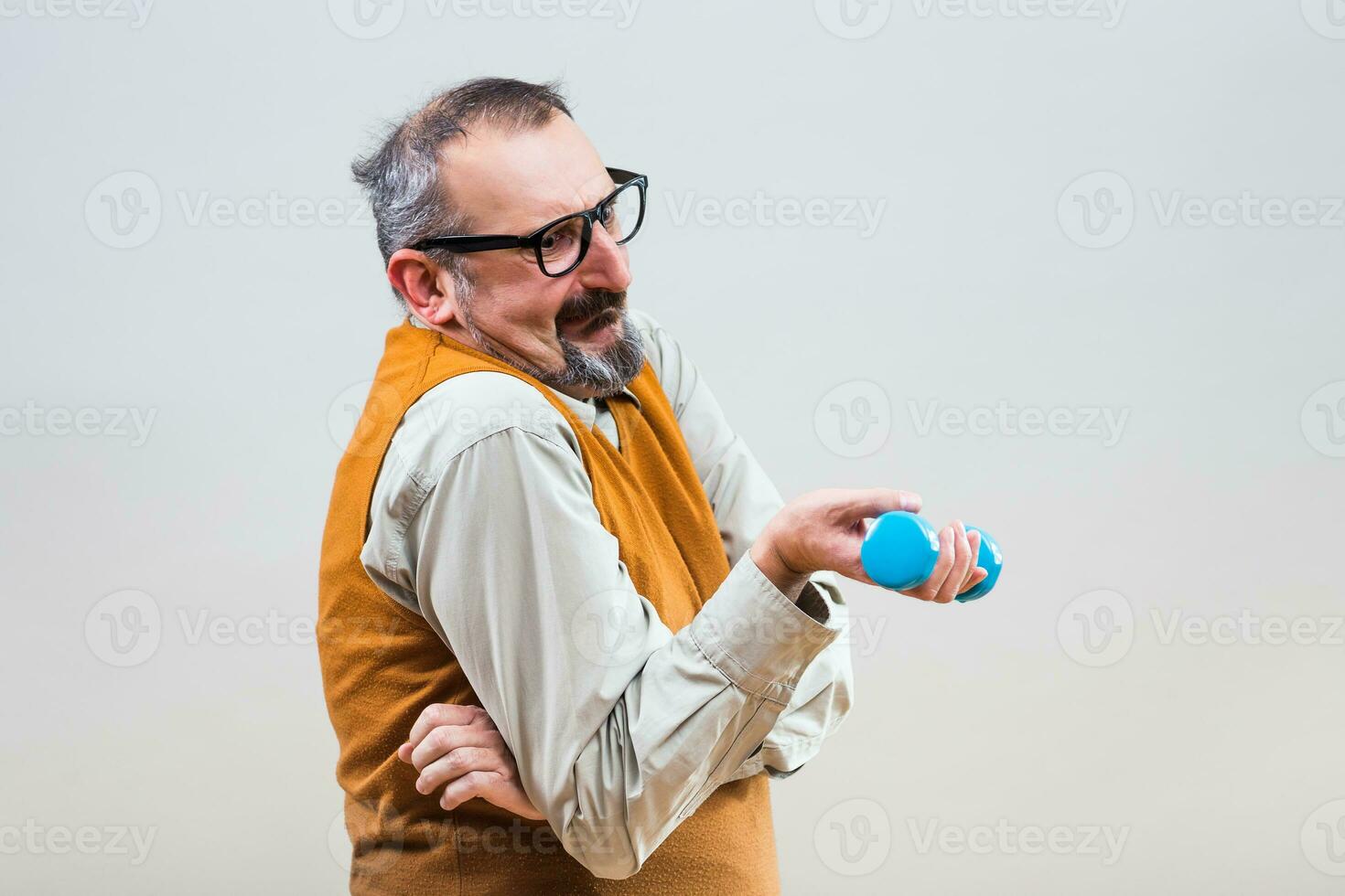 Nerdy businessman is trying to exercise with weights but they are too heavy for him photo