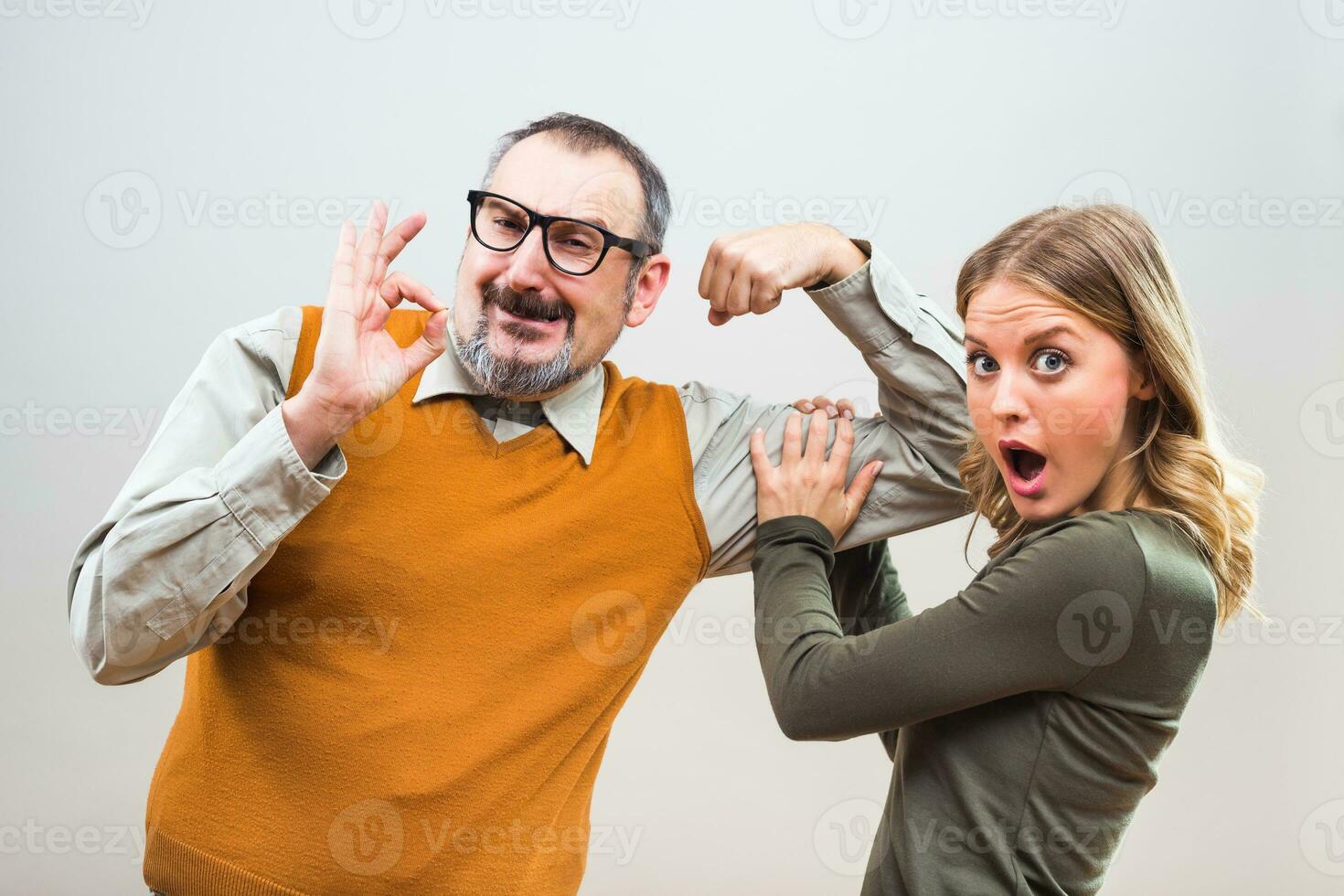 Nerdy man is showing to a beautiful woman how strong he is and she is impresseD photo