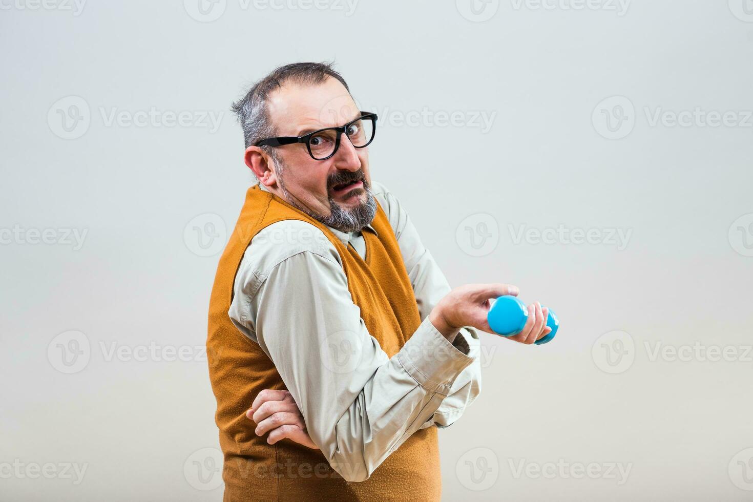 Nerdy businessman is trying to exercise with weights but they are too heavy for him photo