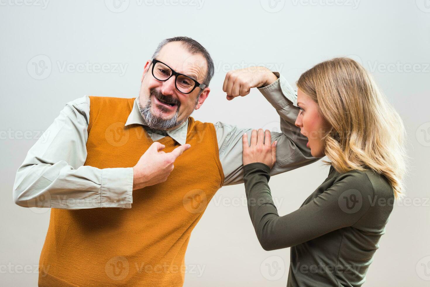 Nerdy man is showing to a beautiful woman how strong he is and she is impressed photo