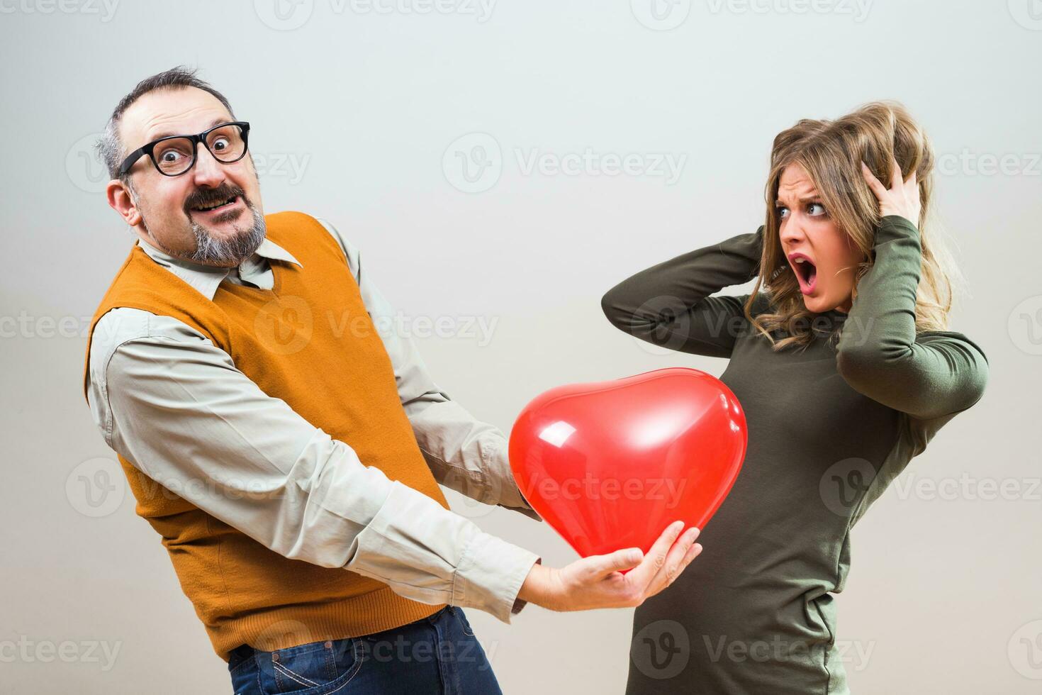 Nerdy man wants to give heart shape balloon to a beautiful woman to show her his love,but she is not interested,she is terrified. photo