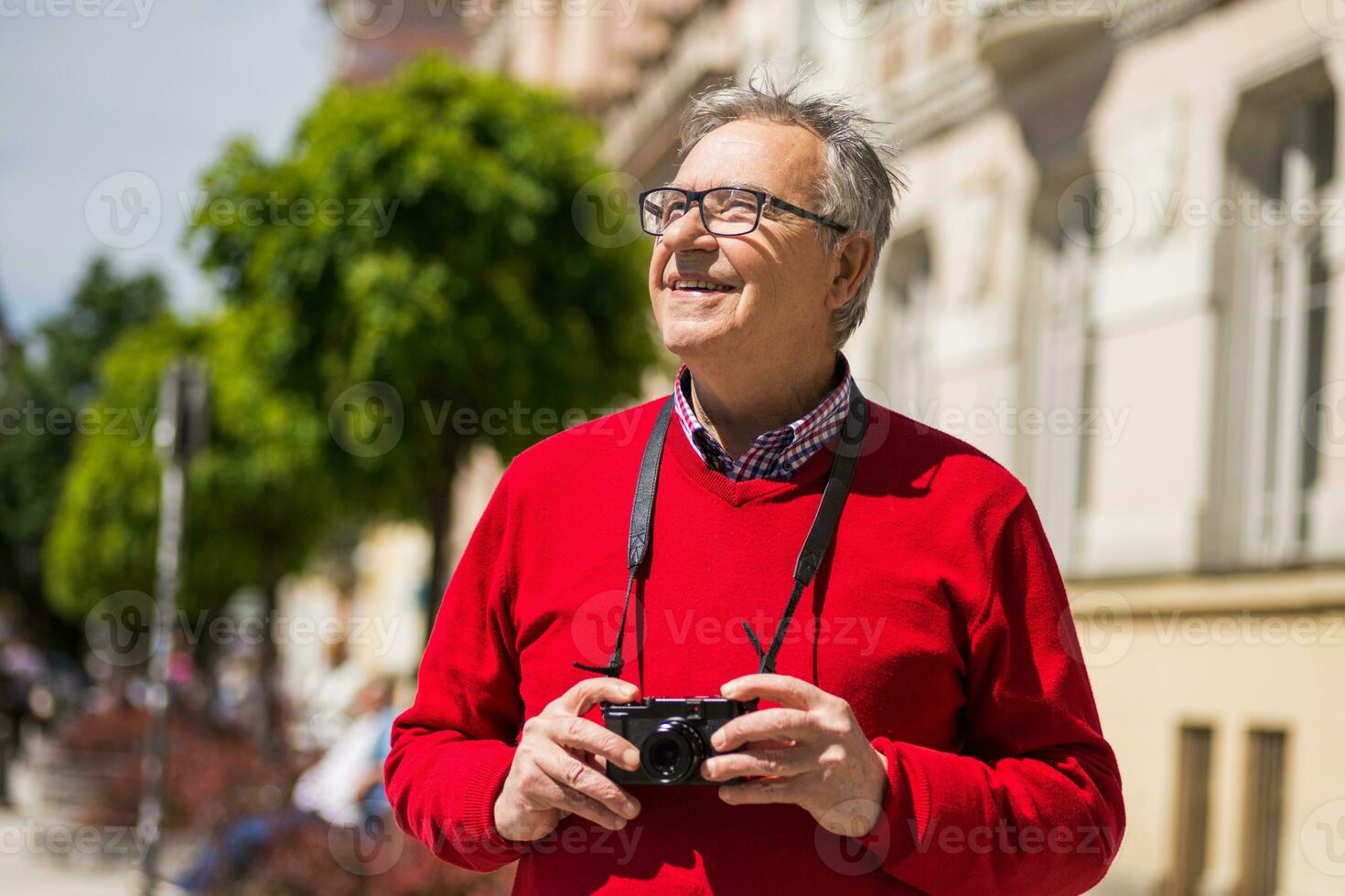 Senior man tourist enjoys photographing at the city photo