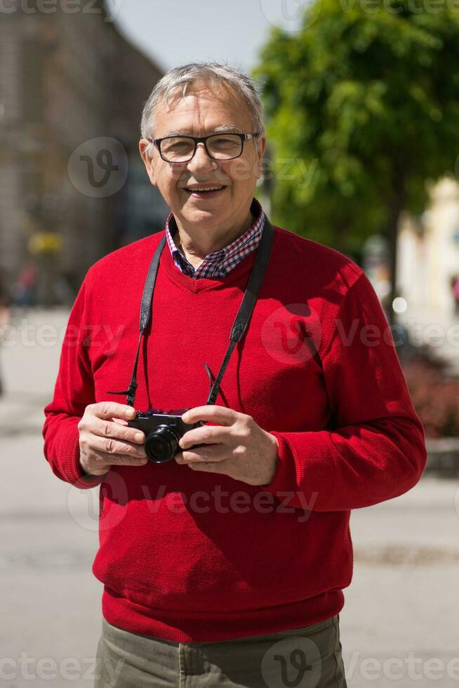 Senior man tourist enjoys photographing at the city photo