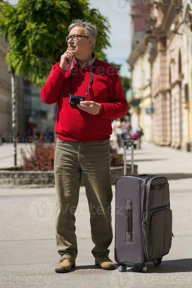 Senior man tourist has come to the city on a vacation but he doesn't know which way to go photo