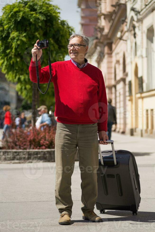 mayor hombre turista disfruta fotografiando a el ciudad foto