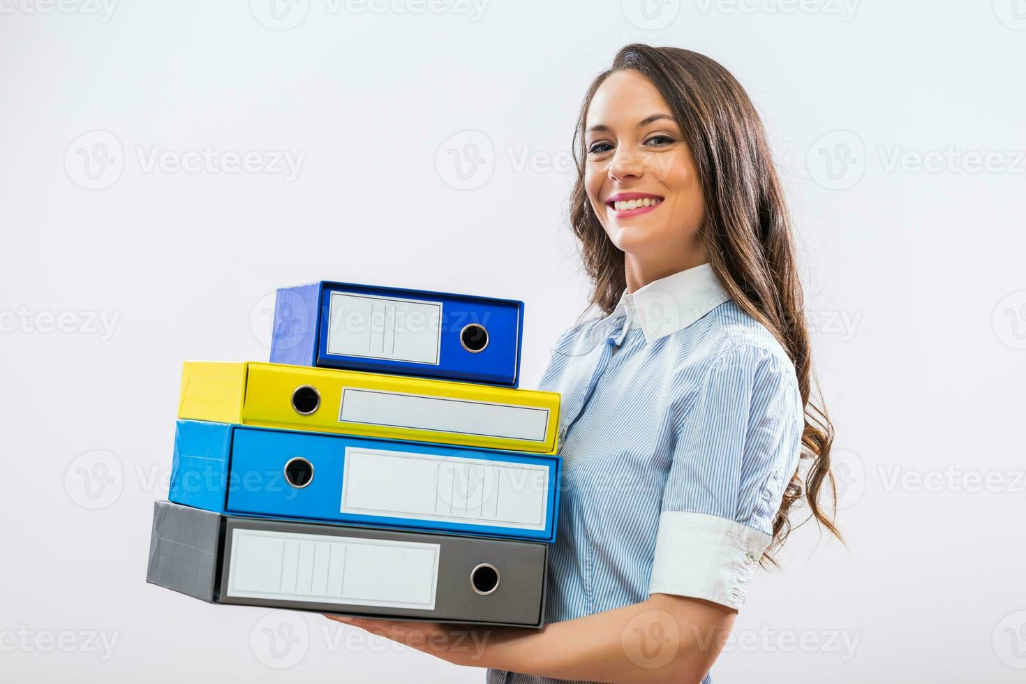 Portrait of happy businesswoman holding office archives on gray background photo