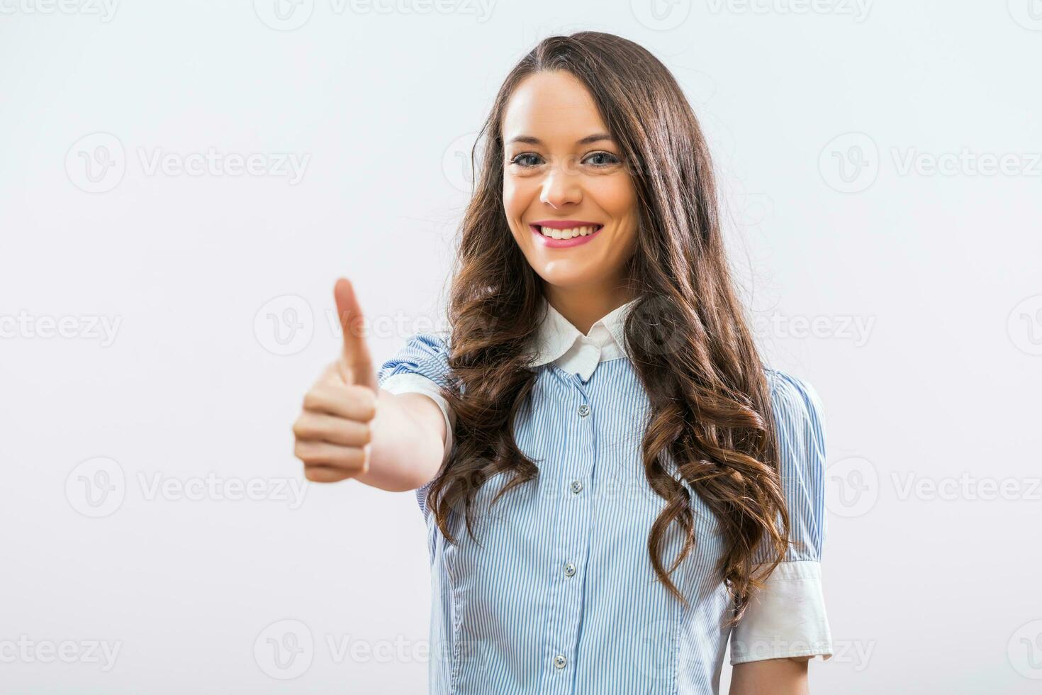 Portrait of beautiful businesswoman showing thumb up on gray background photo