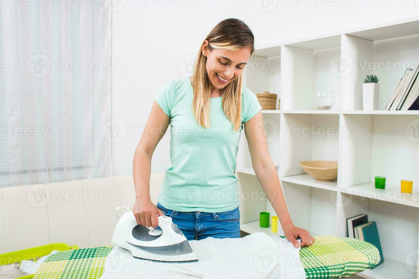 Beautiful woman ironing clothes at her home photo