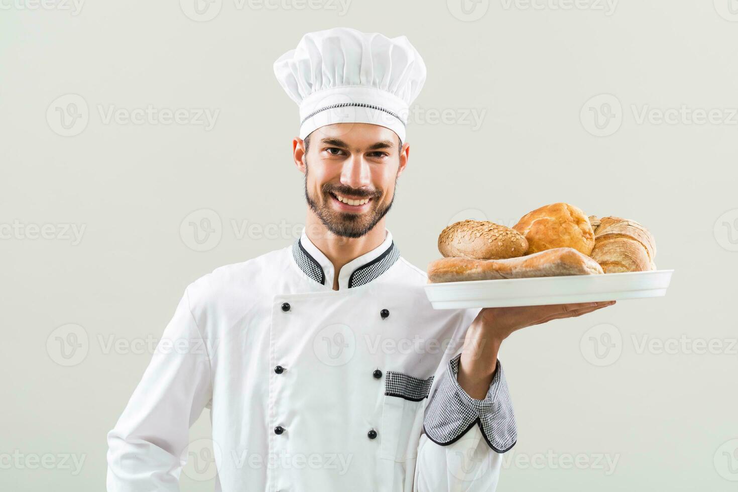 Baker holding bunch of bread on gray background photo