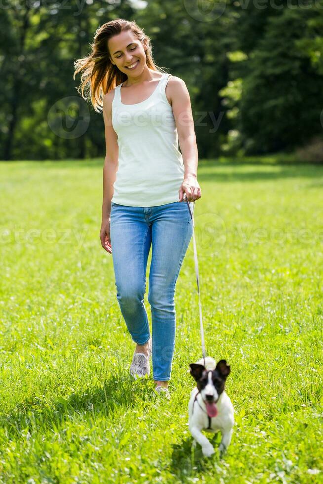 Beautiful woman enjoys walking with her cute dog Jack Russell Terrier in the nature photo