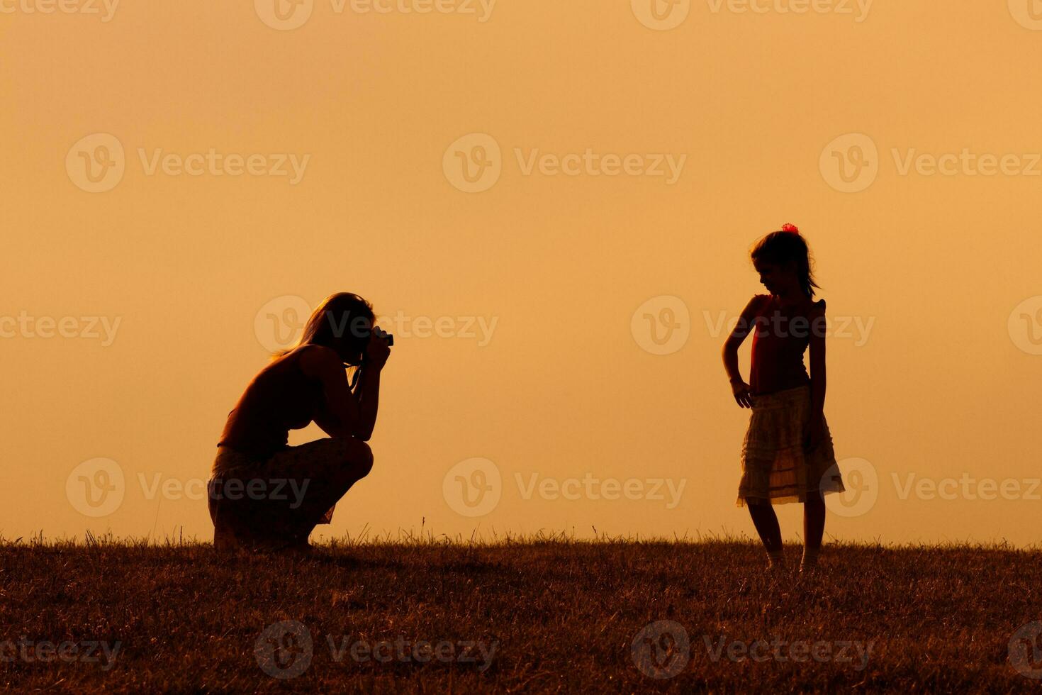 Silhouette of a mother photographing daughter photo