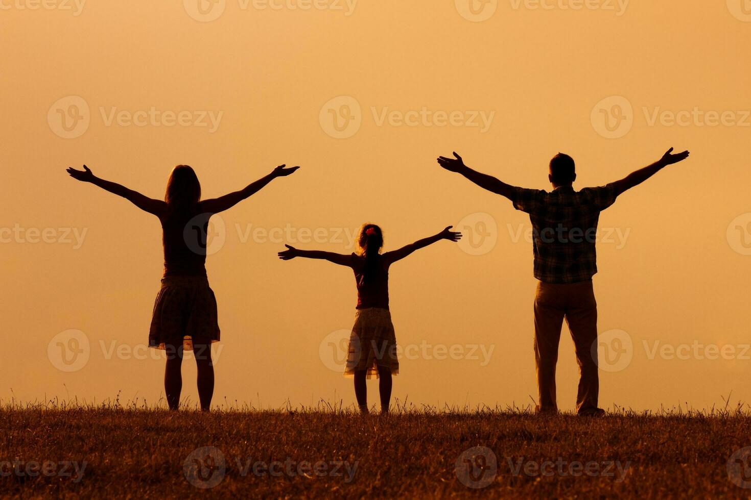 Parents enjoy watching sunset with their daughter photo