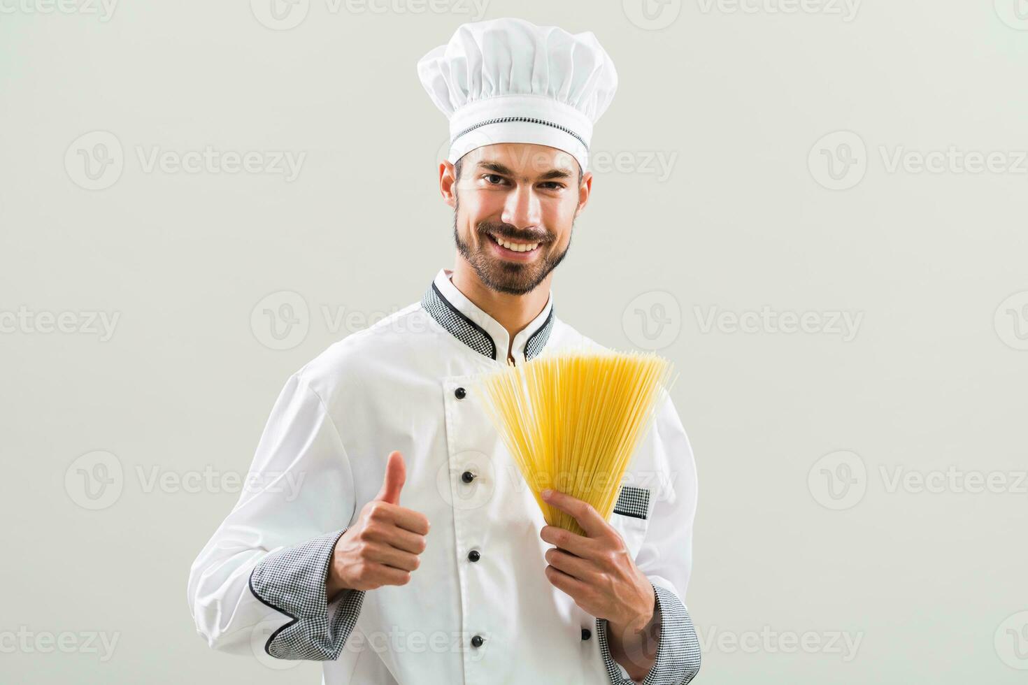 Chef is holding spaghetti and showing thumb up on gray background photo