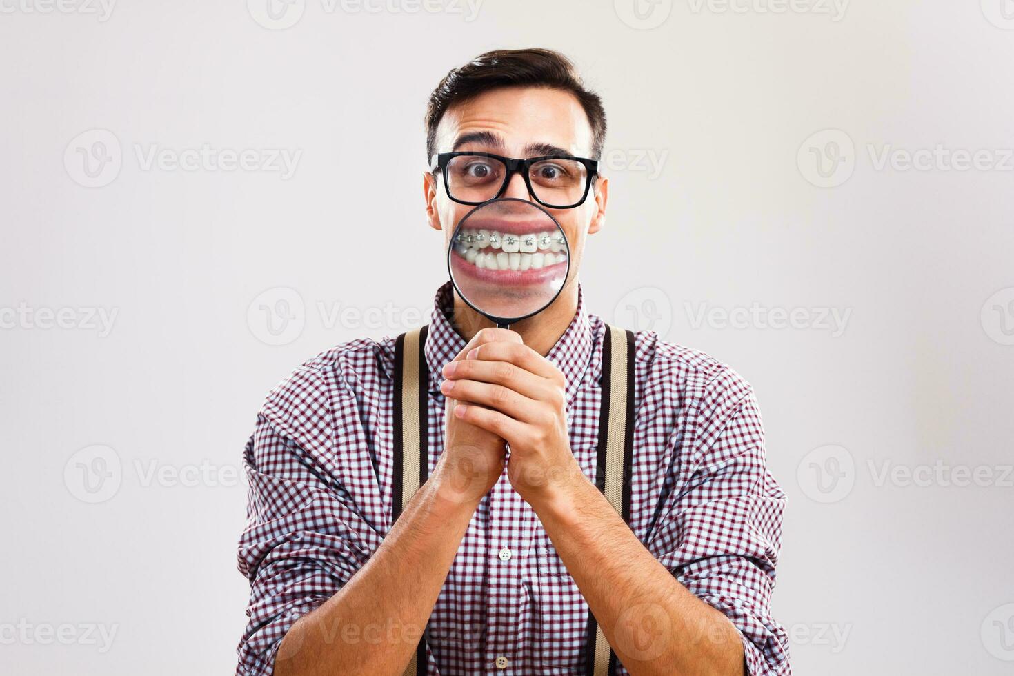 Nerdy man is showing his braces with magnifying glass photo