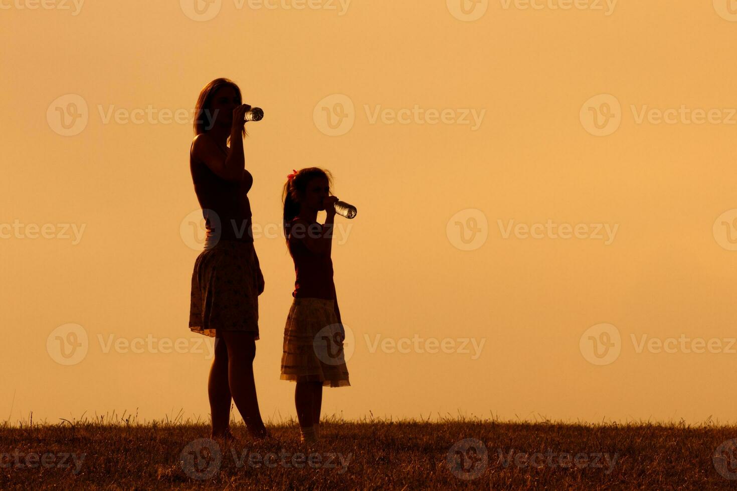 madre y hija son Bebiendo agua a puesta de sol foto