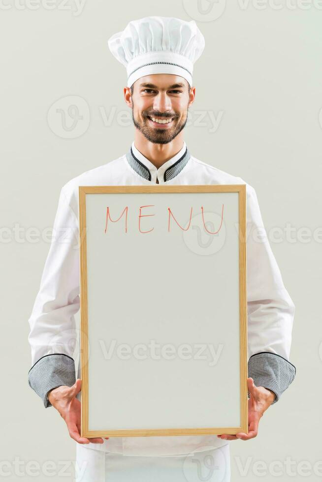 Chef is holding whiteboard on gray background. photo