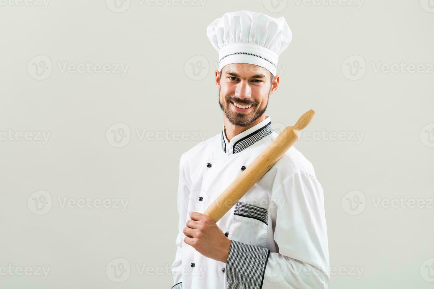Portrait of chef holding rolling pin on gray background photo