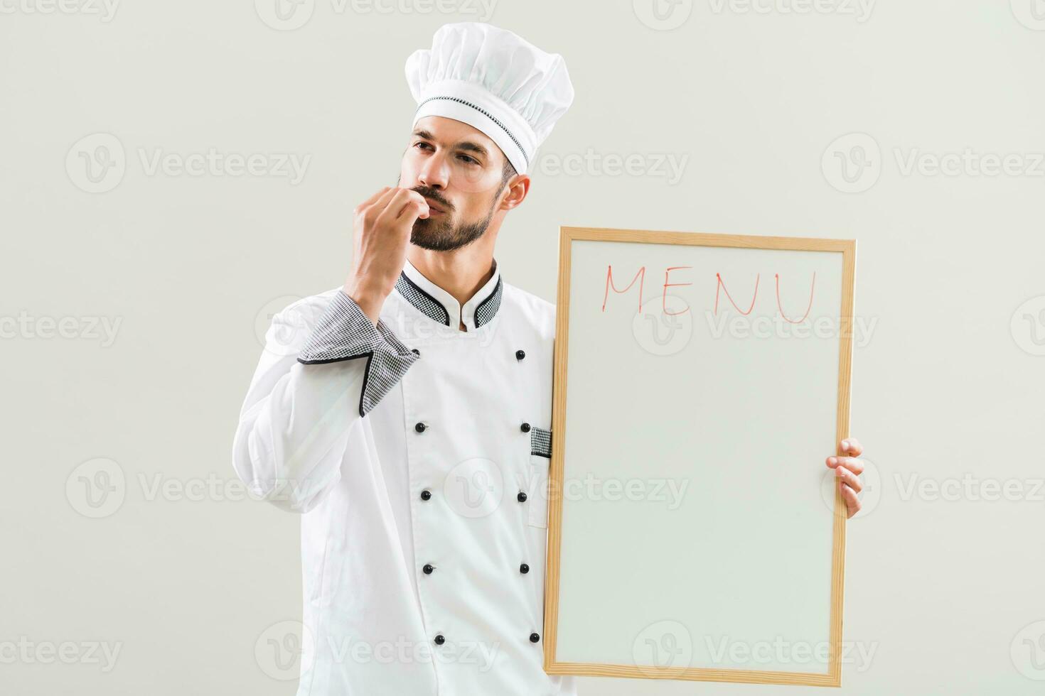 Chef is showing delicious sign and whiteboard on gray background photo