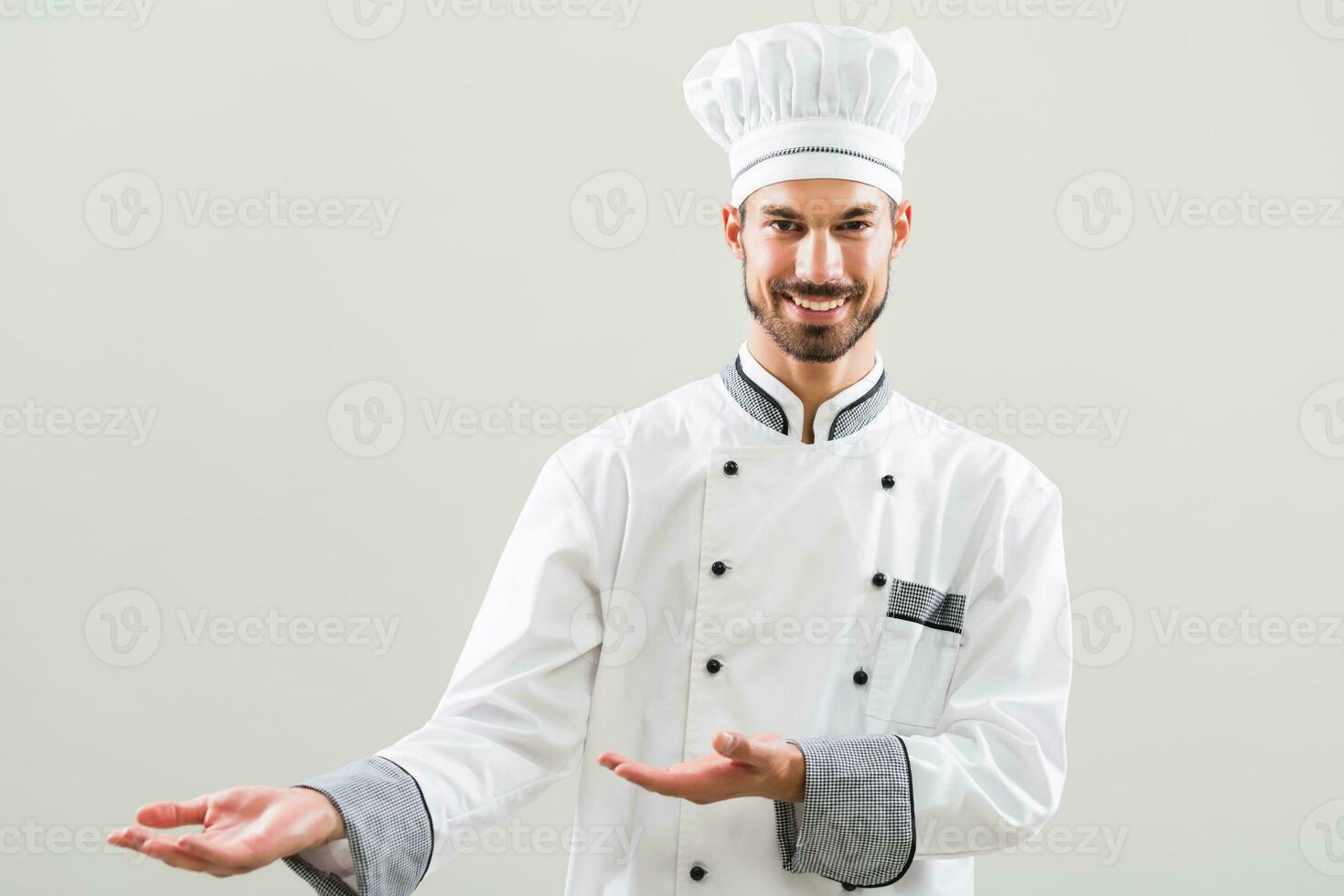 Smiling chef showing welcome gesture on gray background photo