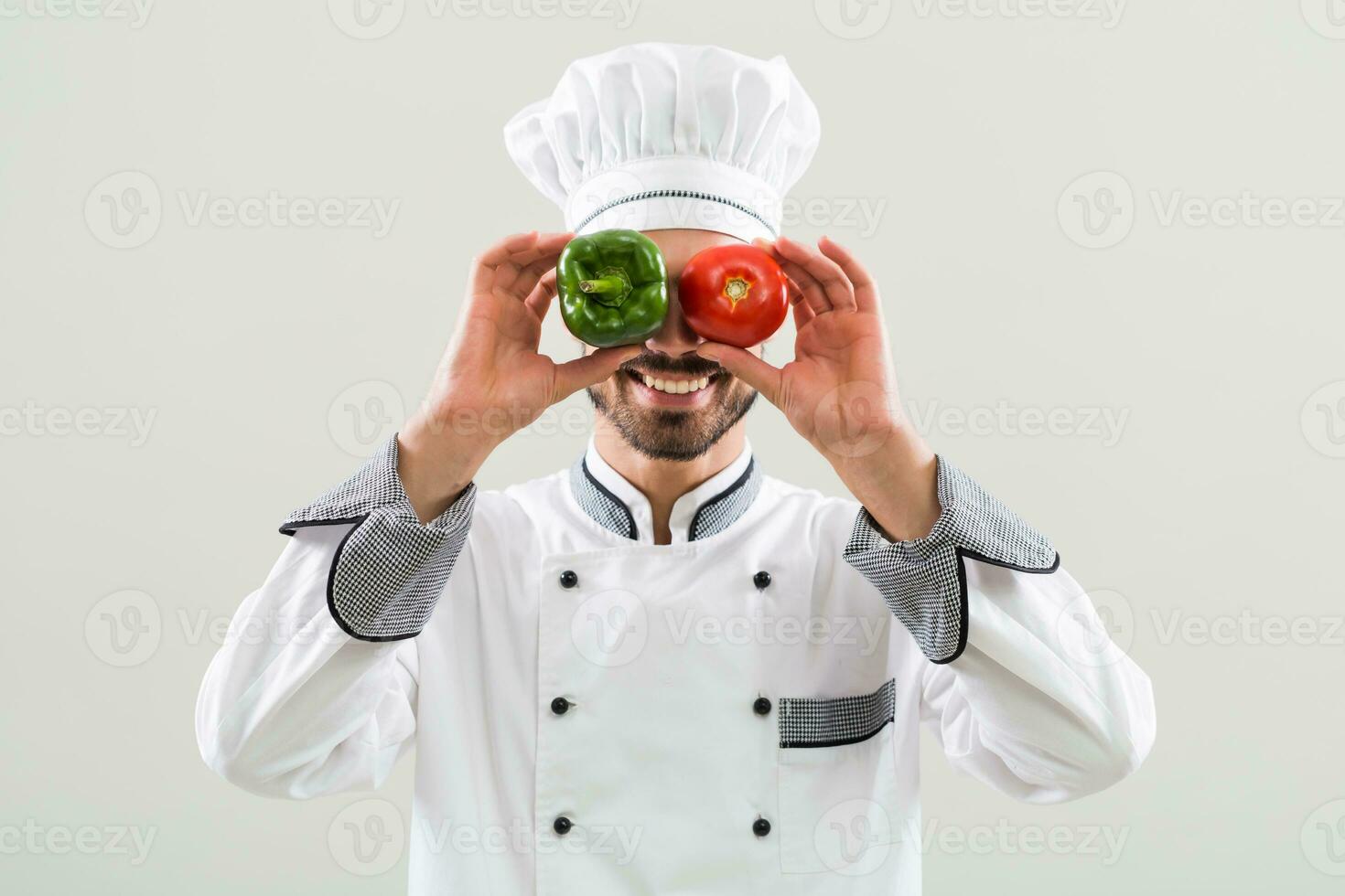 Chef is having fun with vegetables on gray background. photo