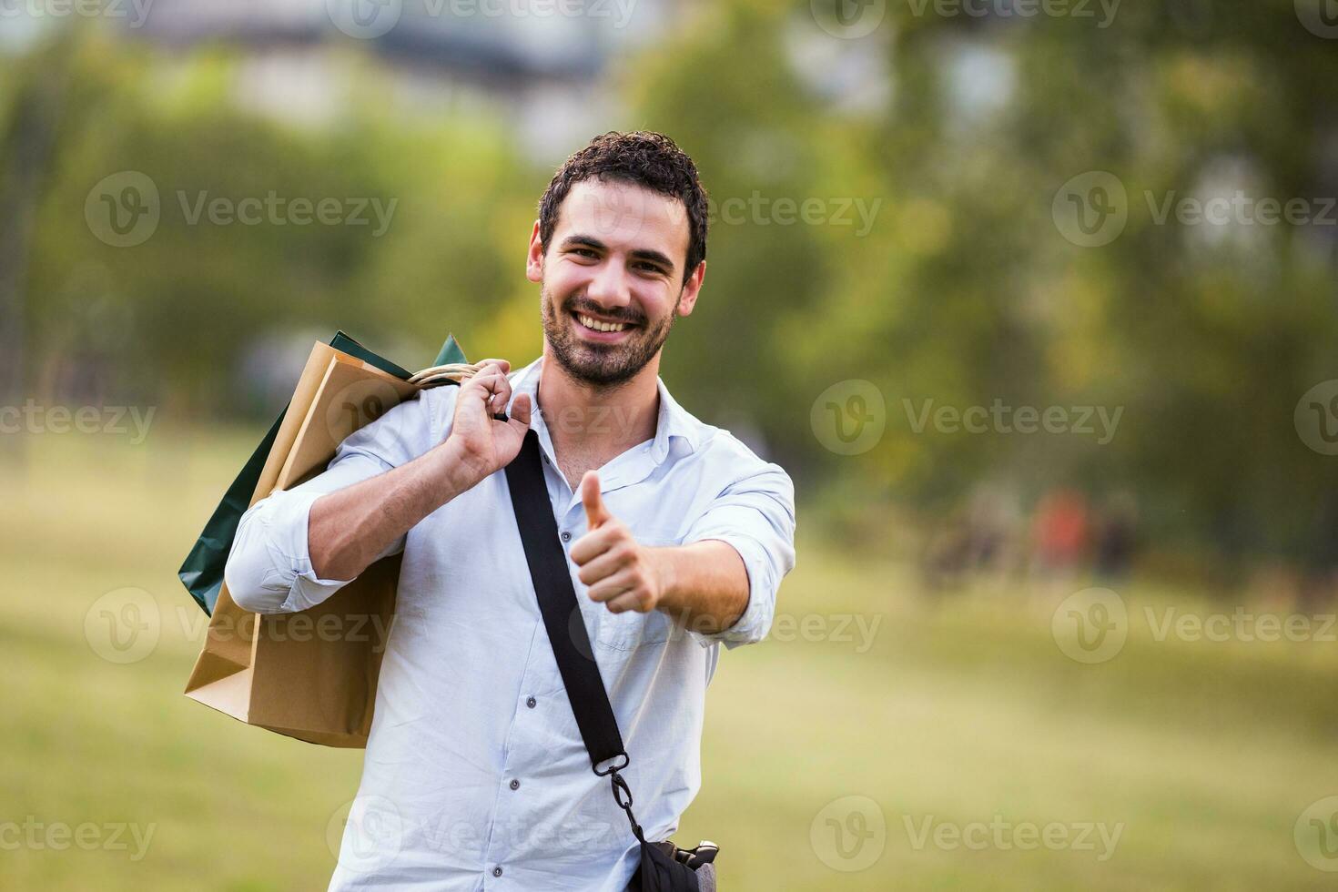 Young businessman took a break from work to go for a shopping and showing thumb up photo