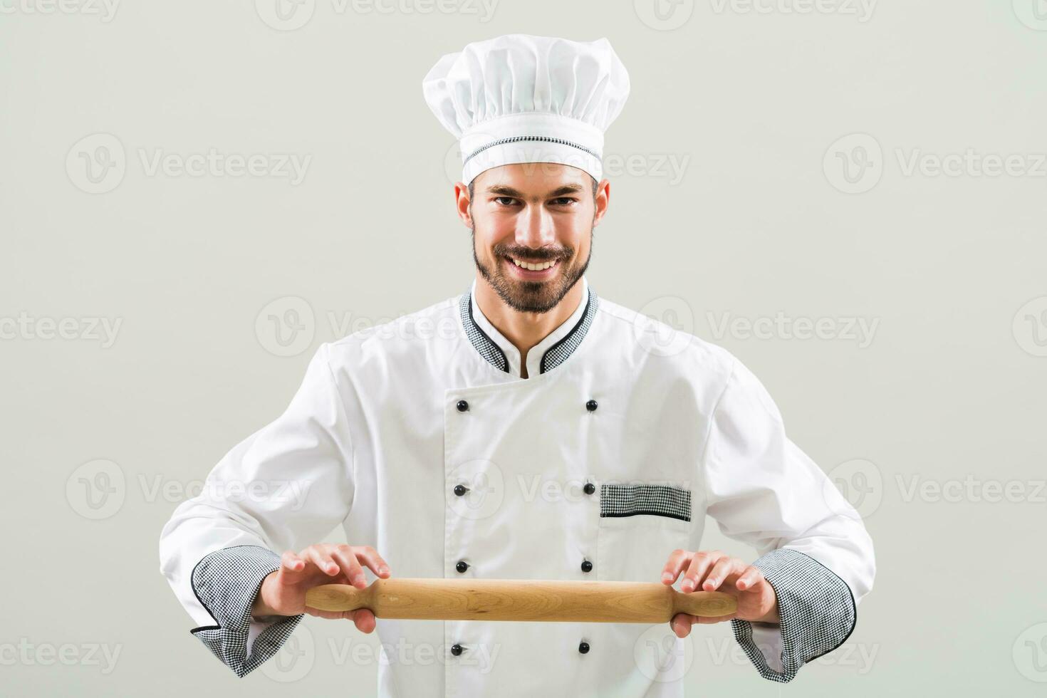 Portrait of chef holding rolling pin on gray background photo