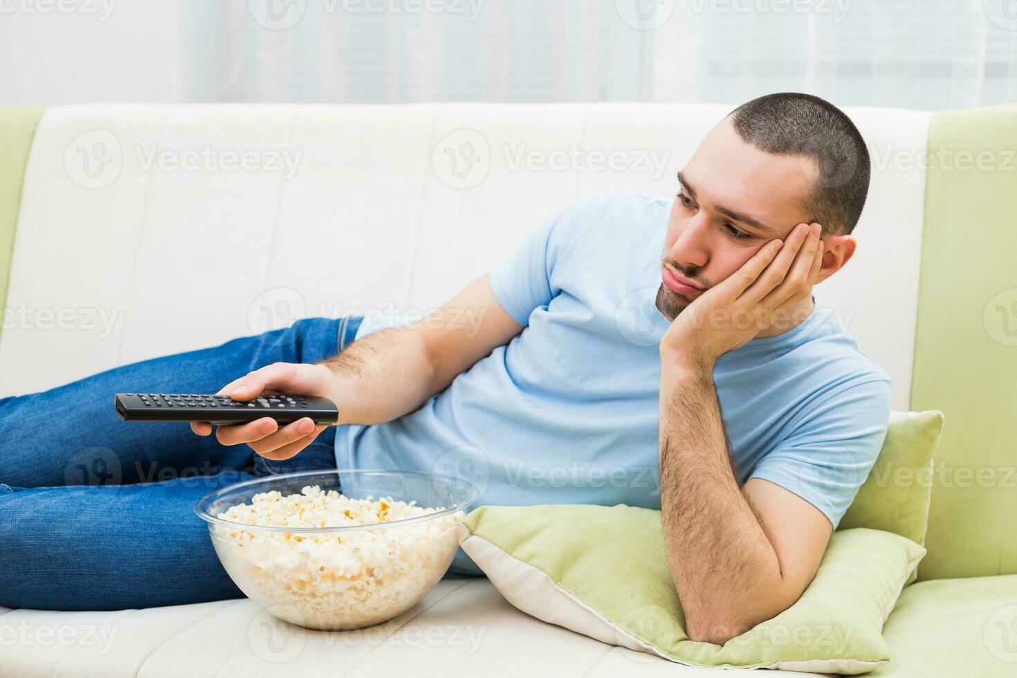 Young man is feeling boredom and changing channels on tv photo