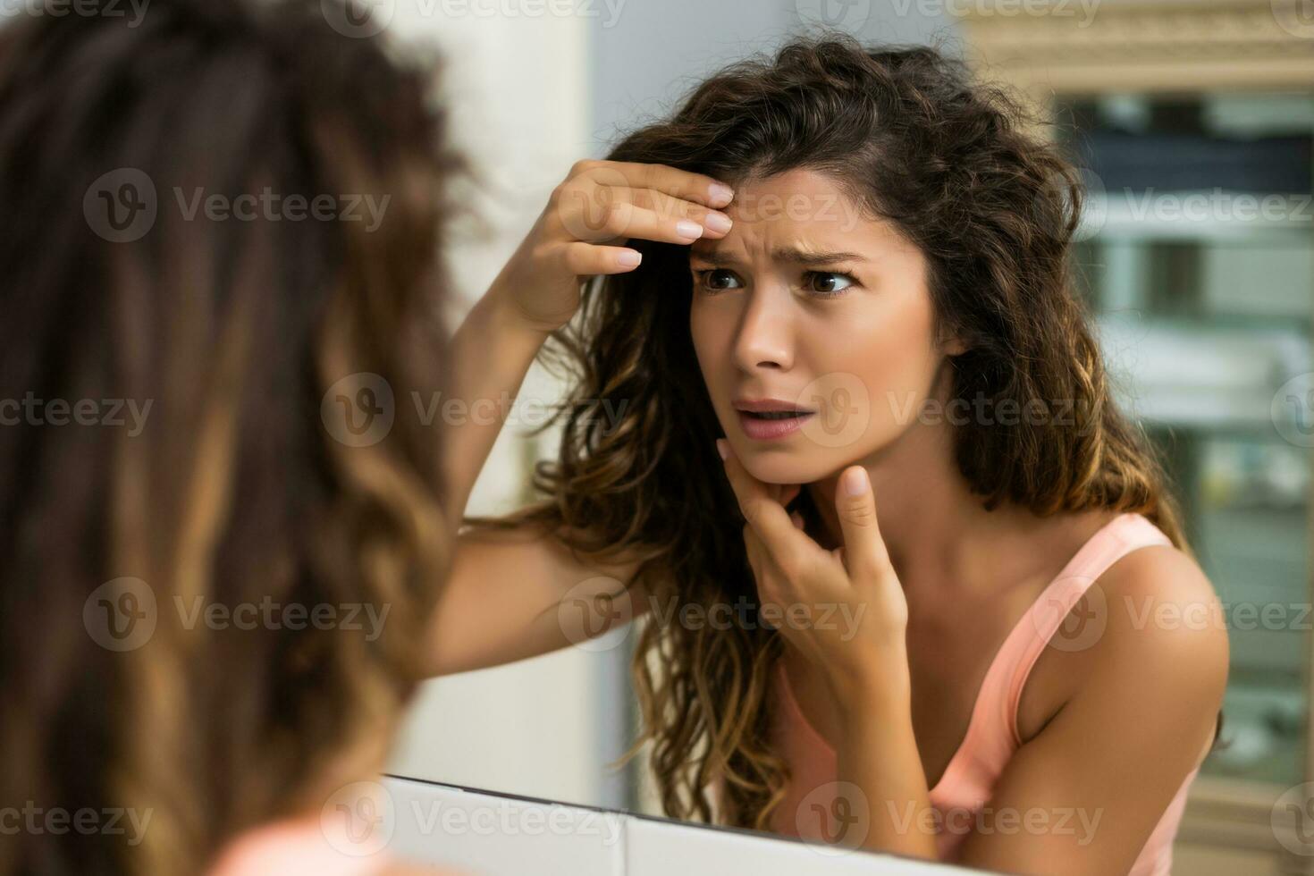 preocupado mujer es mirando su primero arrugas en el baño foto