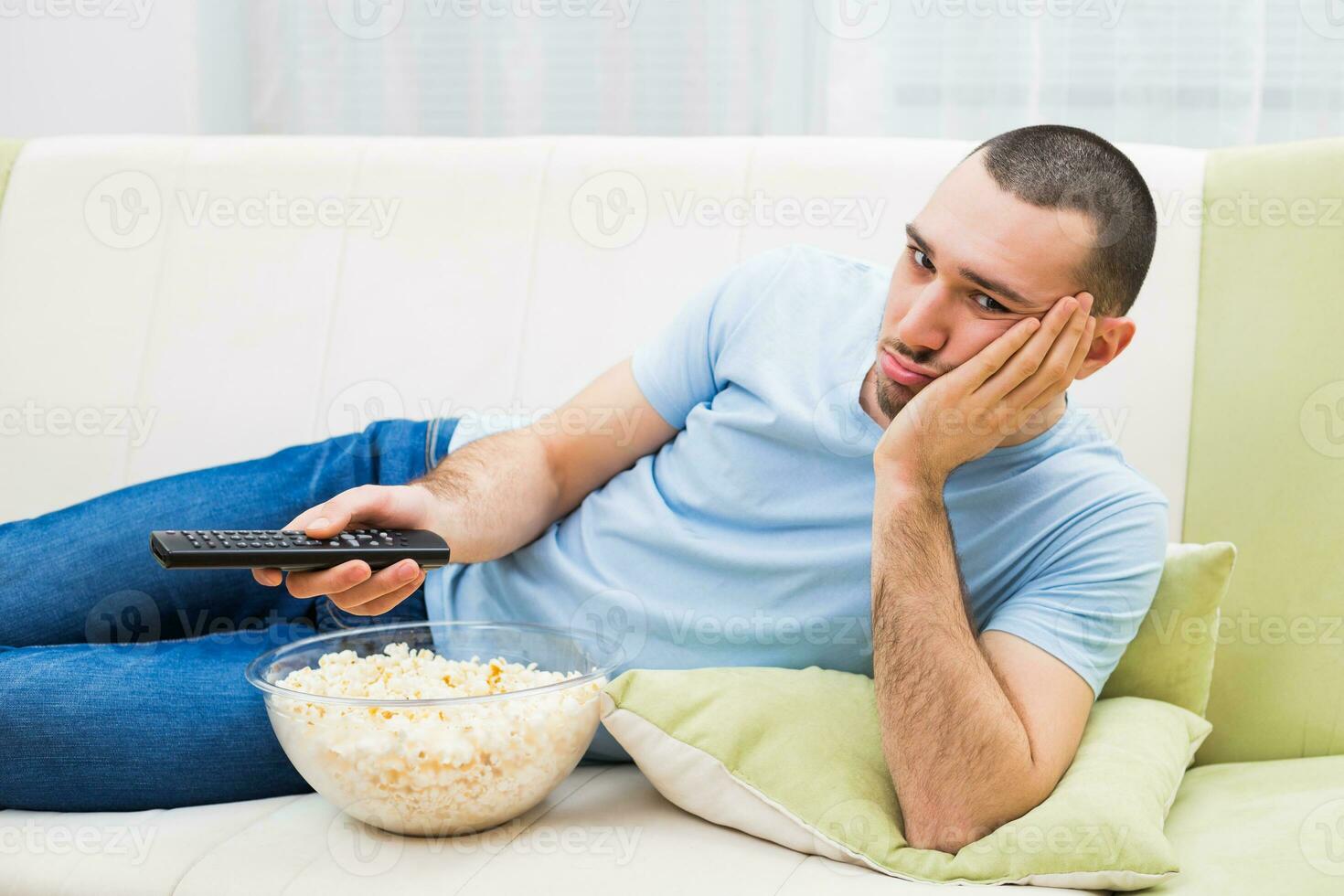Young man is feeling boredom and changing channels on tv photo
