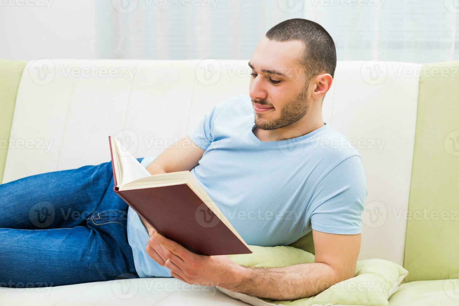 Young man enjoys reading book at his home photo