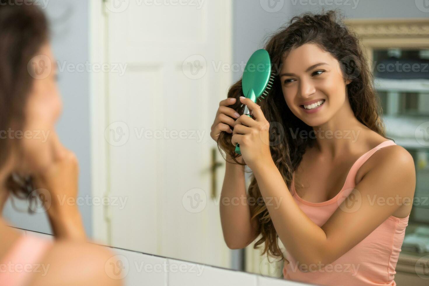 hermosa mujer peinada su pelo en el baño foto