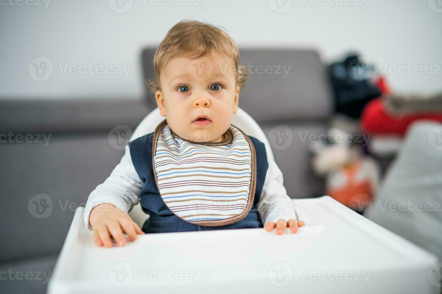 Portrait of cute baby boy sitting in a high chair photo