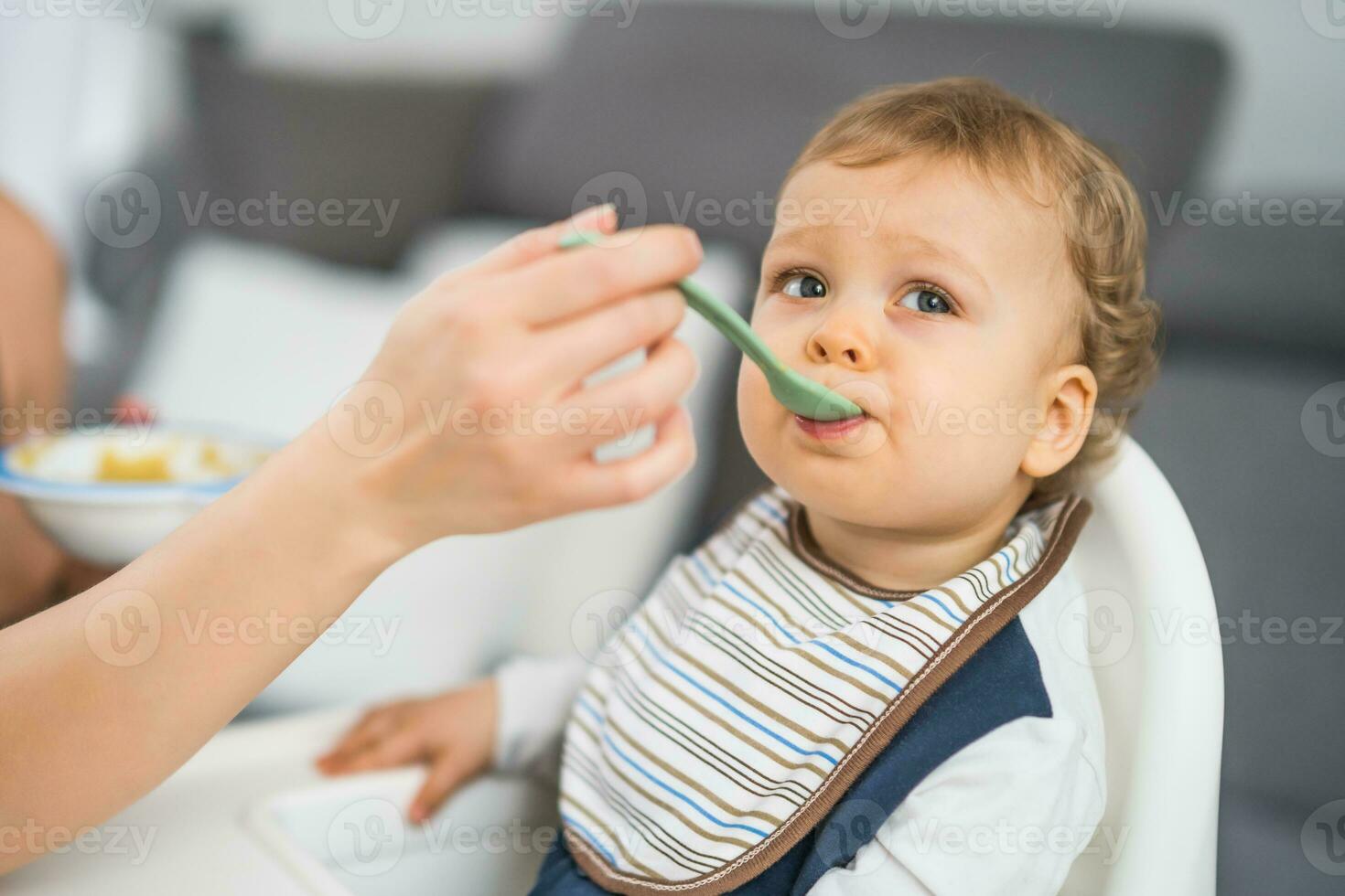 Cute baby boy eating while sitting in a high chair photo