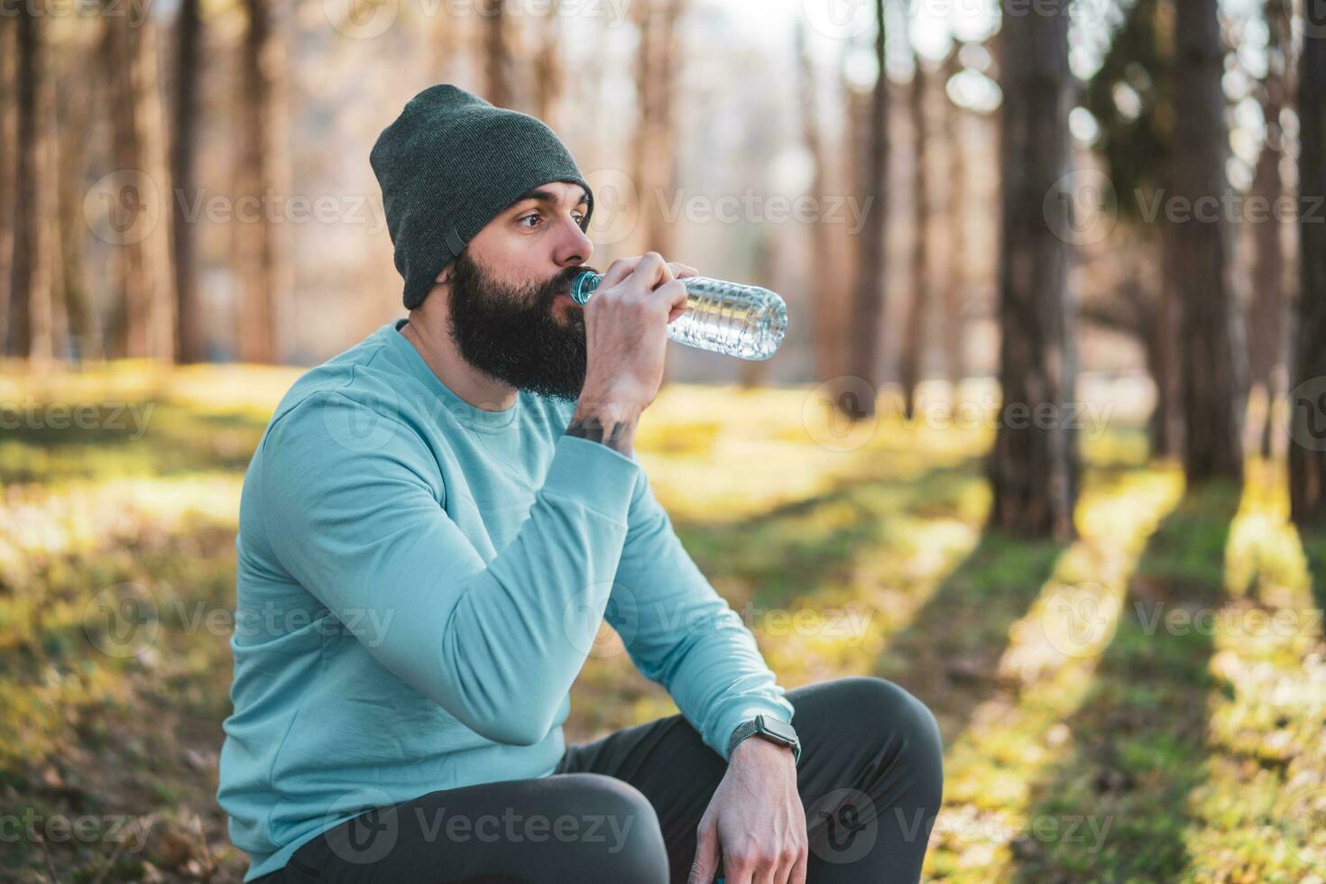 hombre descansando después ejercicio y Bebiendo agua en el naturaleza foto