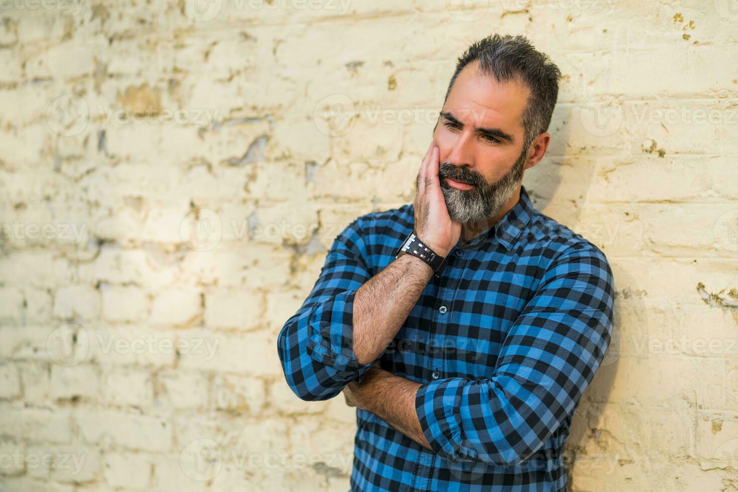 Depressed businessman with beard standing in front of wall outdoor photo